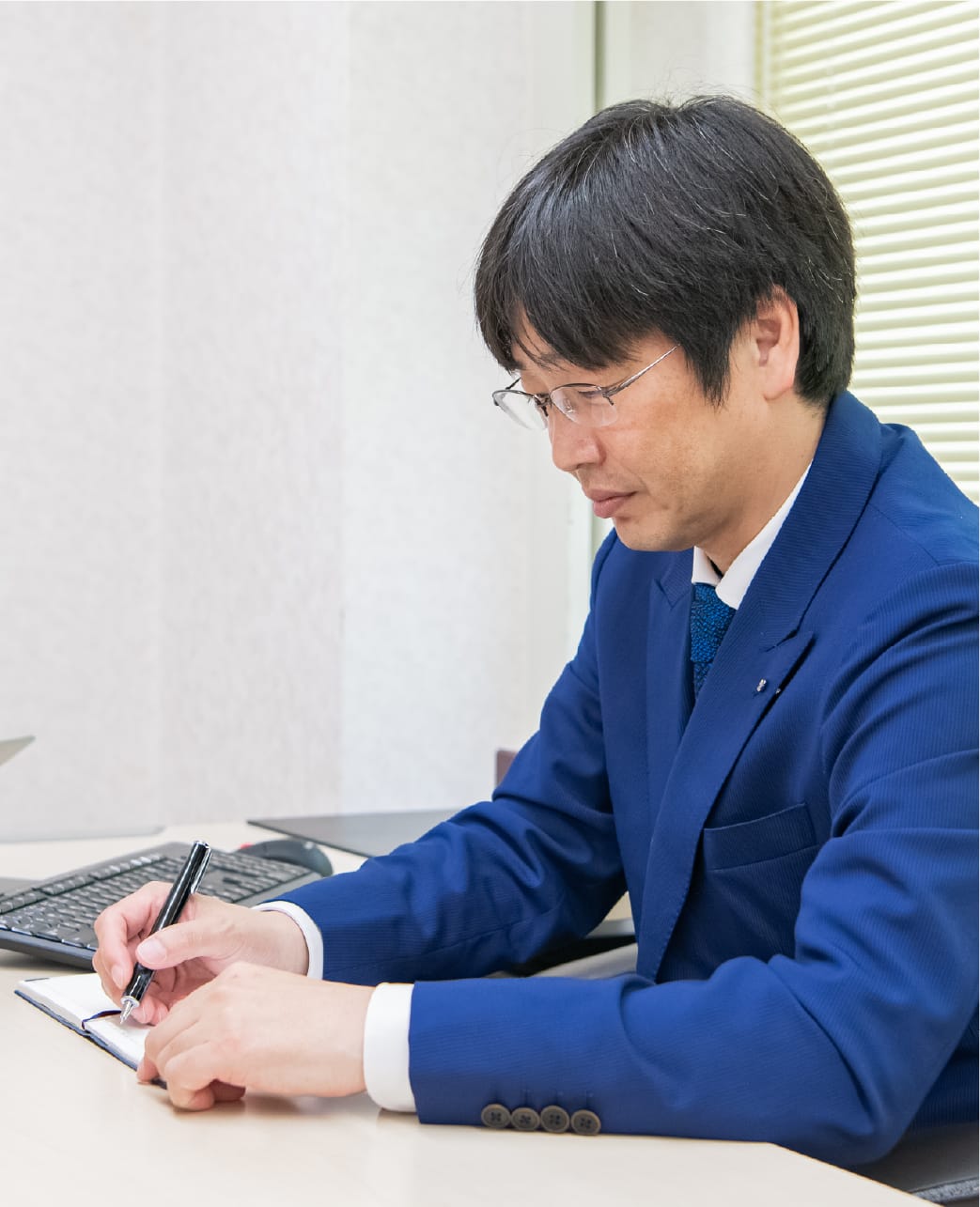 ノートに記入する作業服姿の男性